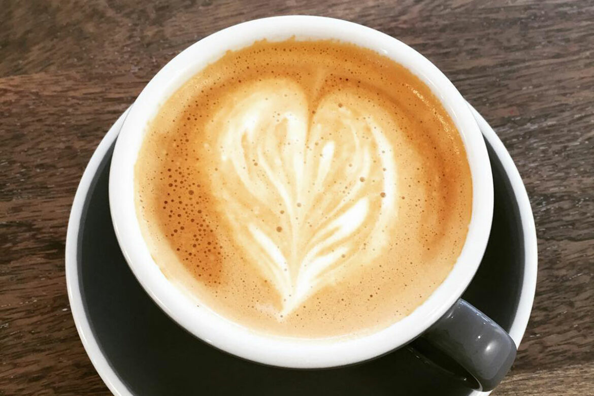 a black and white mug of coffee featuring a heart created with cream