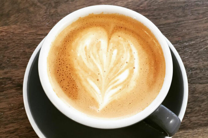 a black and white mug of coffee featuring a heart created with cream