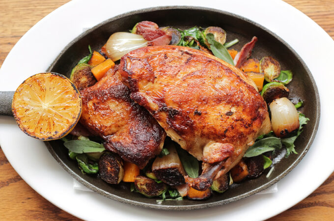 roasted chicken dinner with veggies and lemon in cast iron pan
