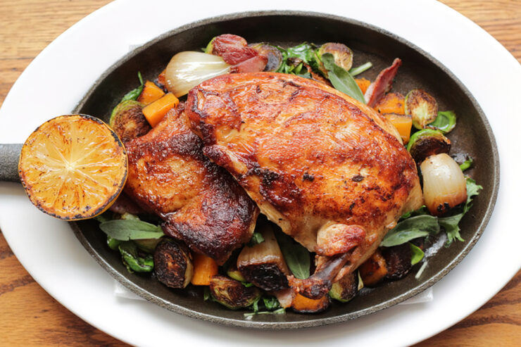 roasted chicken dinner with veggies and lemon in cast iron pan