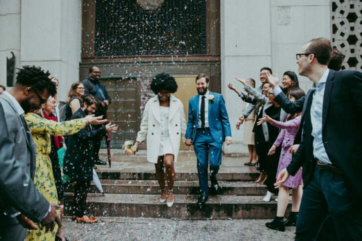 a couple, just married walks through a crowd of wedding attendees throwing confetti